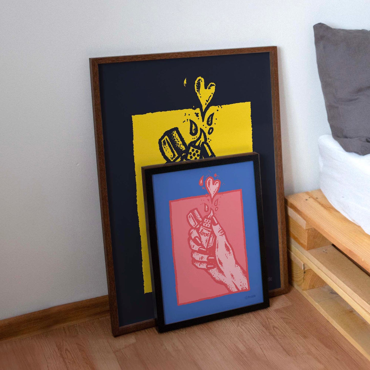Deux affiches posées à côté d'un lit, elles représentent l'affiche d'une main avec un briquet l'une est grande et placé derrière et l'autre et devant.