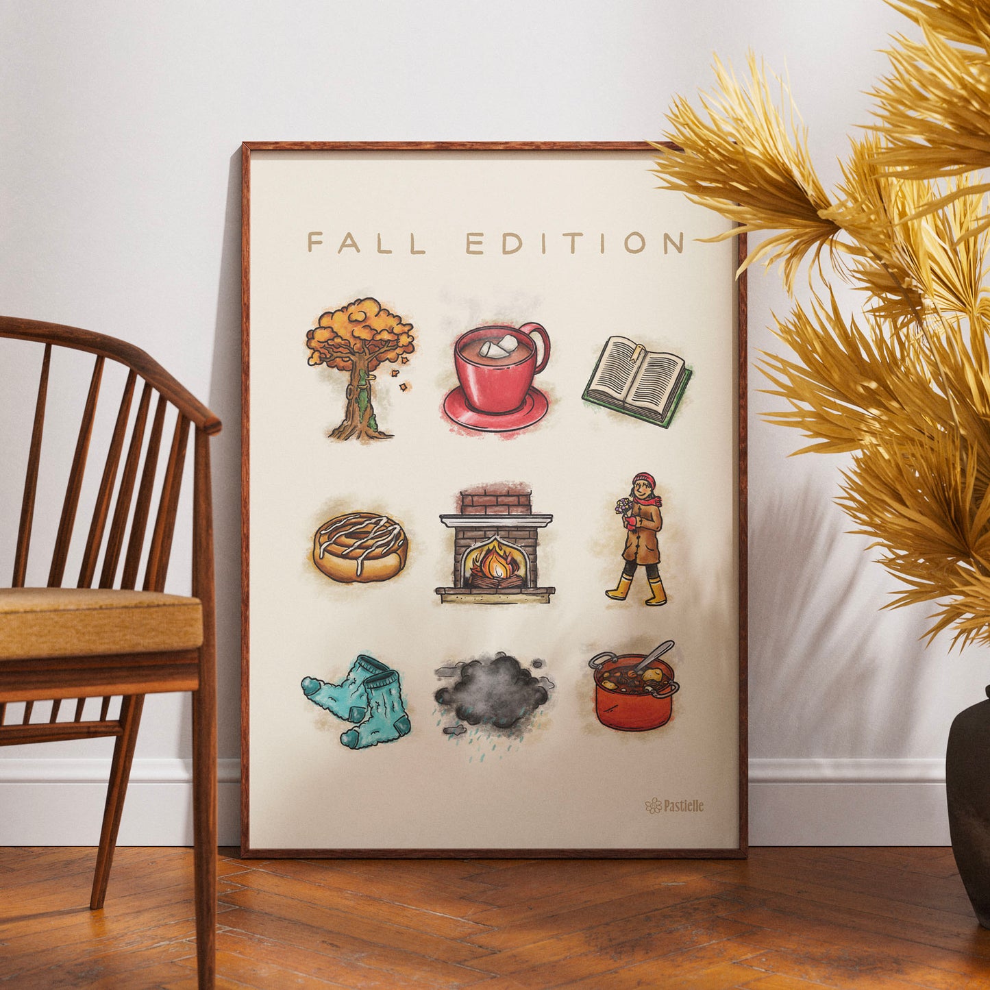 Affiche beige Pastielle, fal edition avec des éléments rappelant l'automne, posée au sol avec une chaise et une plante à côté.