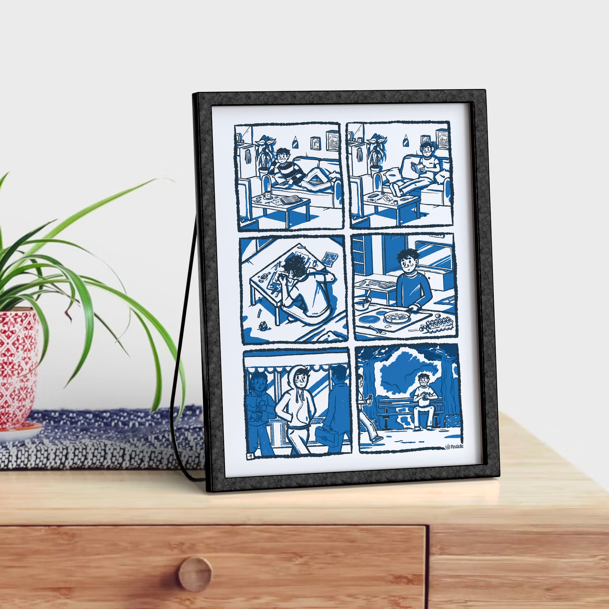 Affiche illustrée Pastielle Camille sur un meuble avec une plante verte