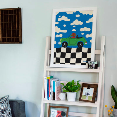 Affiche d'un chien conduisant une voiture posée sur une étagère avec de la décoration dessus