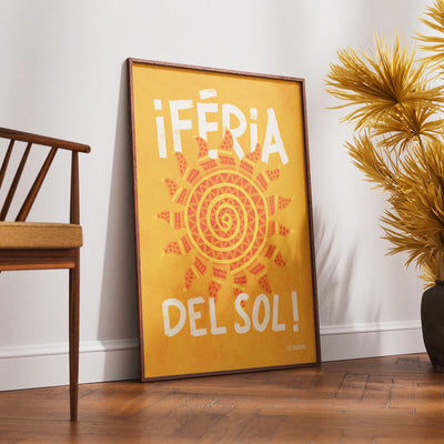 Affiche murale design Pastielle Féria Del Sol – affiche représentant un soleil sur fond jaune avec le titre de l'affiche en blanc, cadre posé au sol avec chaise et plante jaune