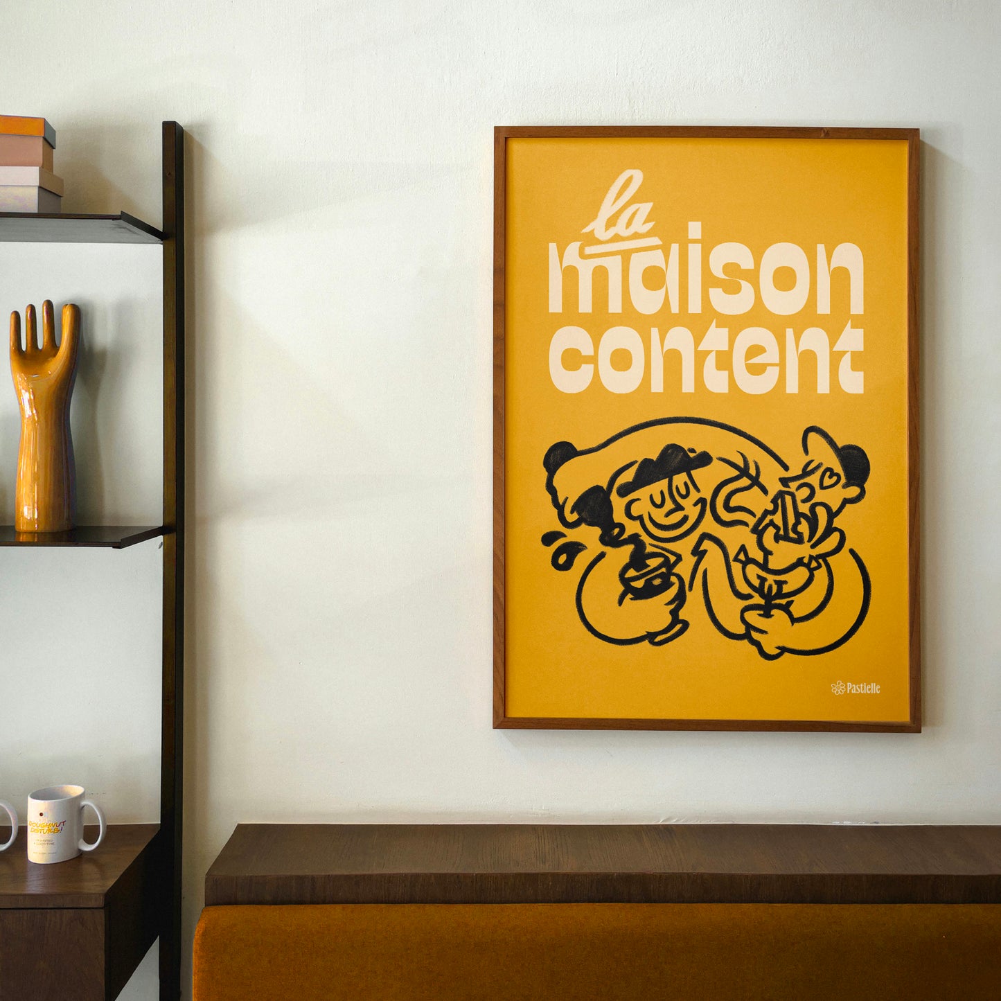 Affiche murale Pastielle La maison content – affiche typographique jaune avec une illustration de deux personnes,  cadre au mur d'un salon avec meubles en bois