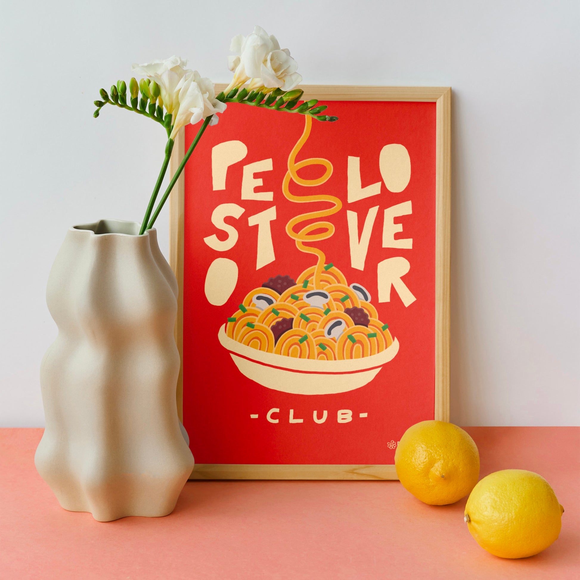 Affiche murale design Pastielle Pesto Lover – affiche représentant un plat de pâtes sur fond orange, cadre posé dans une cuisine rose avec des citrons et un vase blanc